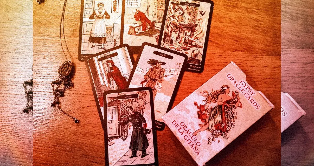 Rozłożone karty cygańskie, w tym "Służąca", "Żołnierz" i "Nieszczęście", obok pudełka "Gypsy Oracle Cards".
