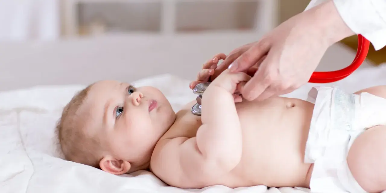 Lekarz osłuchuje niemowlę stetoskopem. Badanie może pomóc w wykryciu chorób metabolicznych u dzieci, lista schorzeń jest długa.