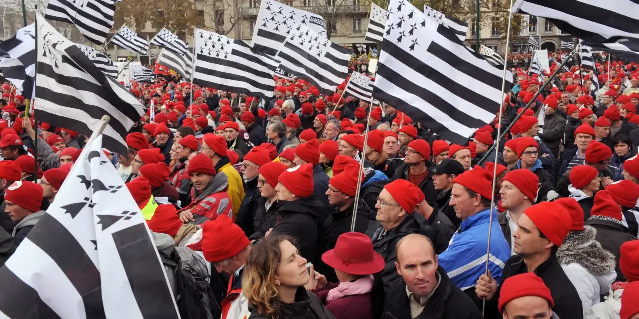 Foule portant le bonnet rouge breton, brandissant des drapeaux bretons.