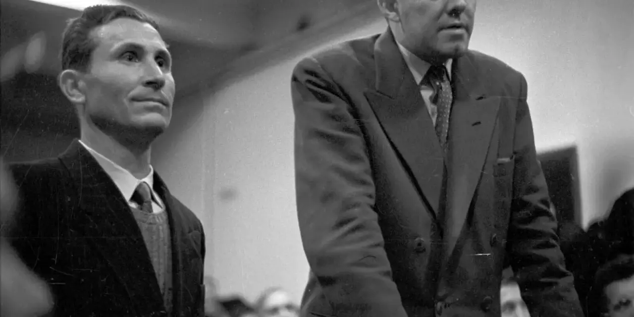 Deux hommes en costume, dont Gustave Dominici, se tiennent debout dans une salle.