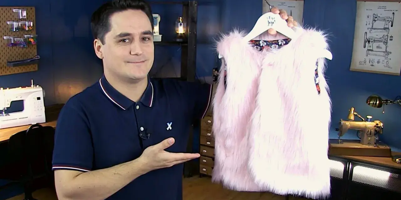 Un homme présente un adorable gilet berger bébé en fausse fourrure rose. Un patron gratuit pour le coudre est disponible.