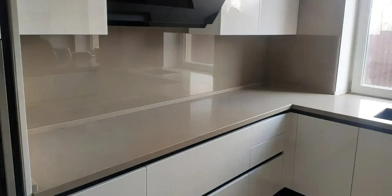 Nowoczesna kuchnia z frontami w kolorze ral9001 i eleganckim, jasnym blatem. Czarny okap dodaje charakteru.
