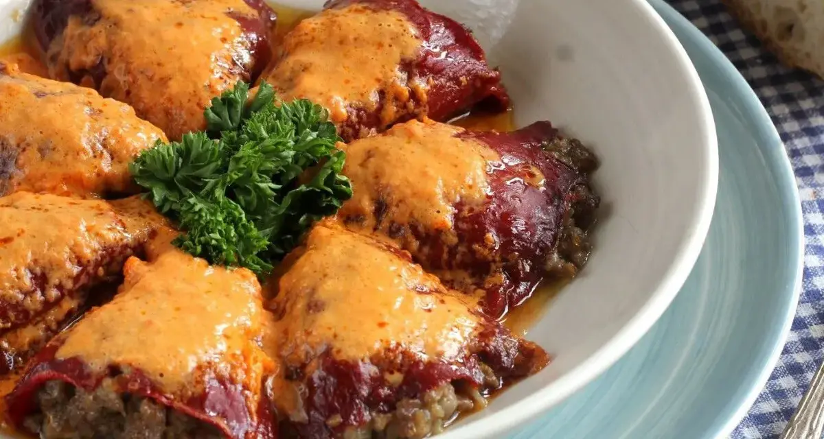 Pimientos rellenos de carne, cubiertos con una cremosa salsa y adornados con perejil fresco. Un plato casero listo para disfrutar.