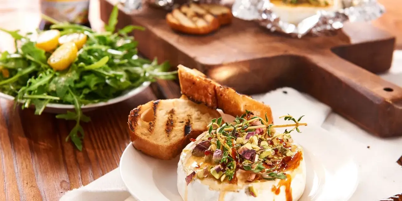 Pyszny camembert z grilla, polany miodem i posypany pistacjami, podany z grzankami i sałatką. Idealny na letnie wieczory.