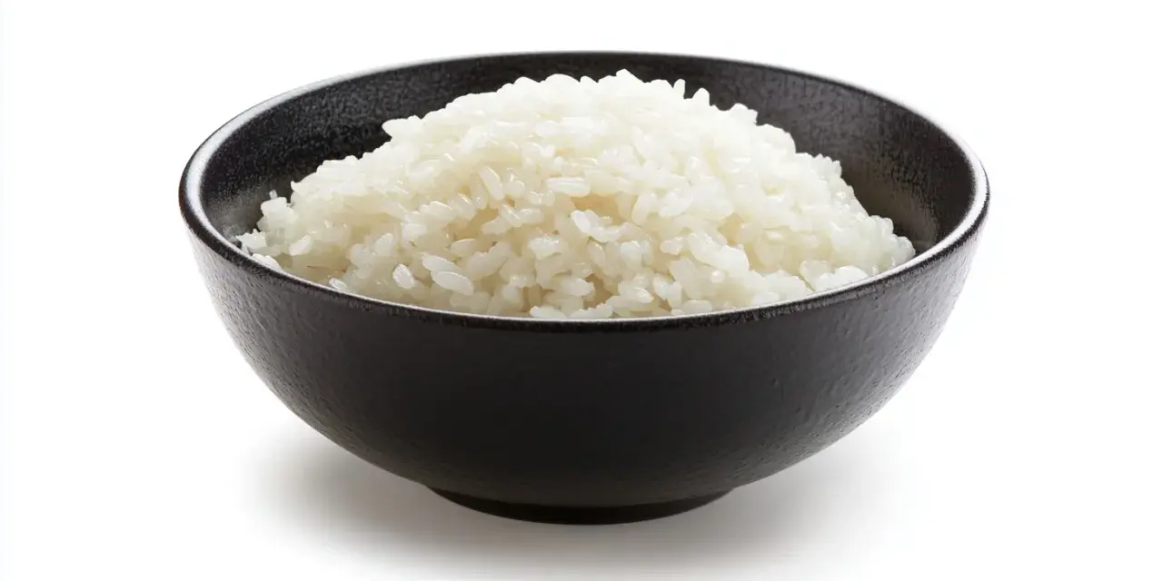 Un tazón negro lleno de arroz blanco esponjoso, listo para ser parte de un delicioso arroz frito.