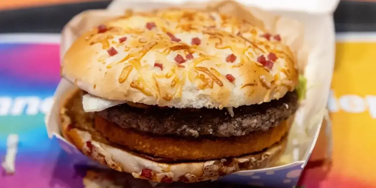 Pyszny burger drwala z podwójnym mięsem, chrupiącym plackiem ziemniaczanym i bułką posypaną serem i kawałkami boczku.