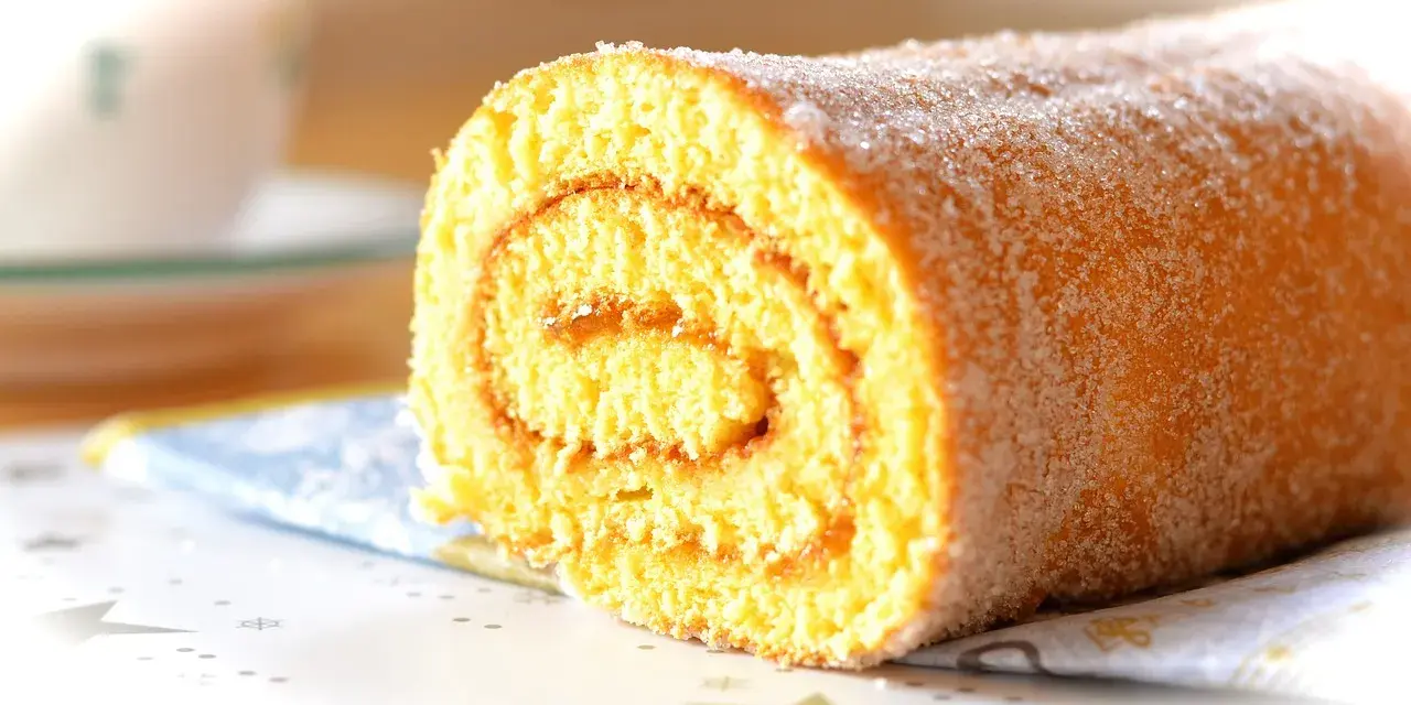 En saftig glutenfri rulltårta med socker strött över, perfekt för fikat.