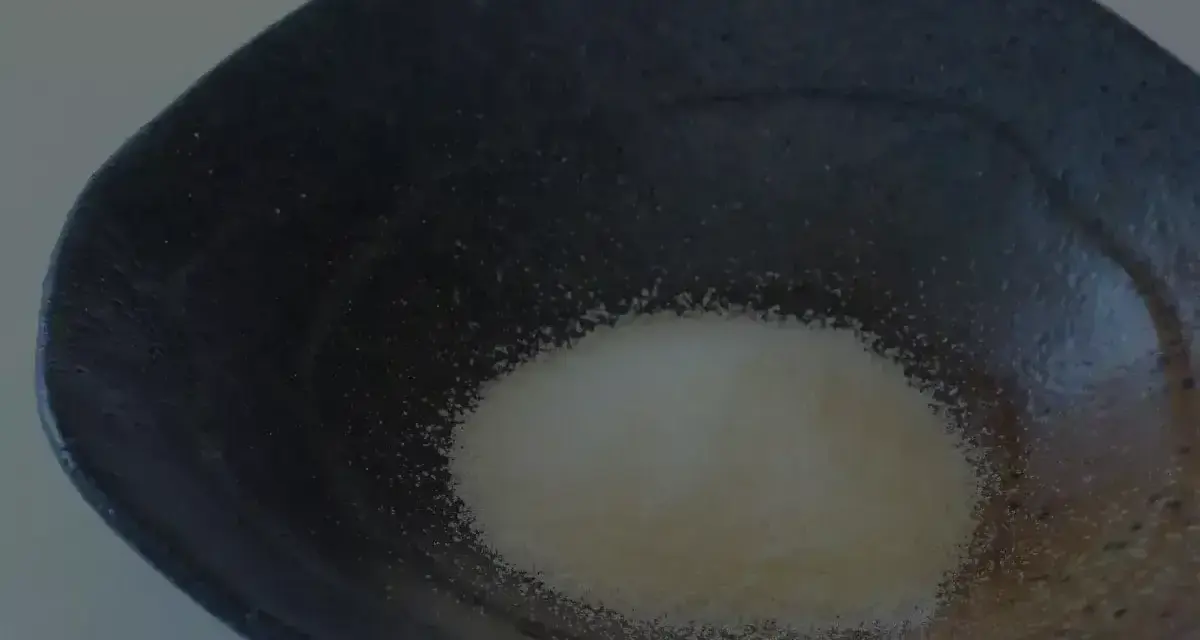 Granulat żelatyny w ciemnej misce. To pierwszy krok, jak rozpuścić żelatynę, by uzyskać idealną konsystencję.
