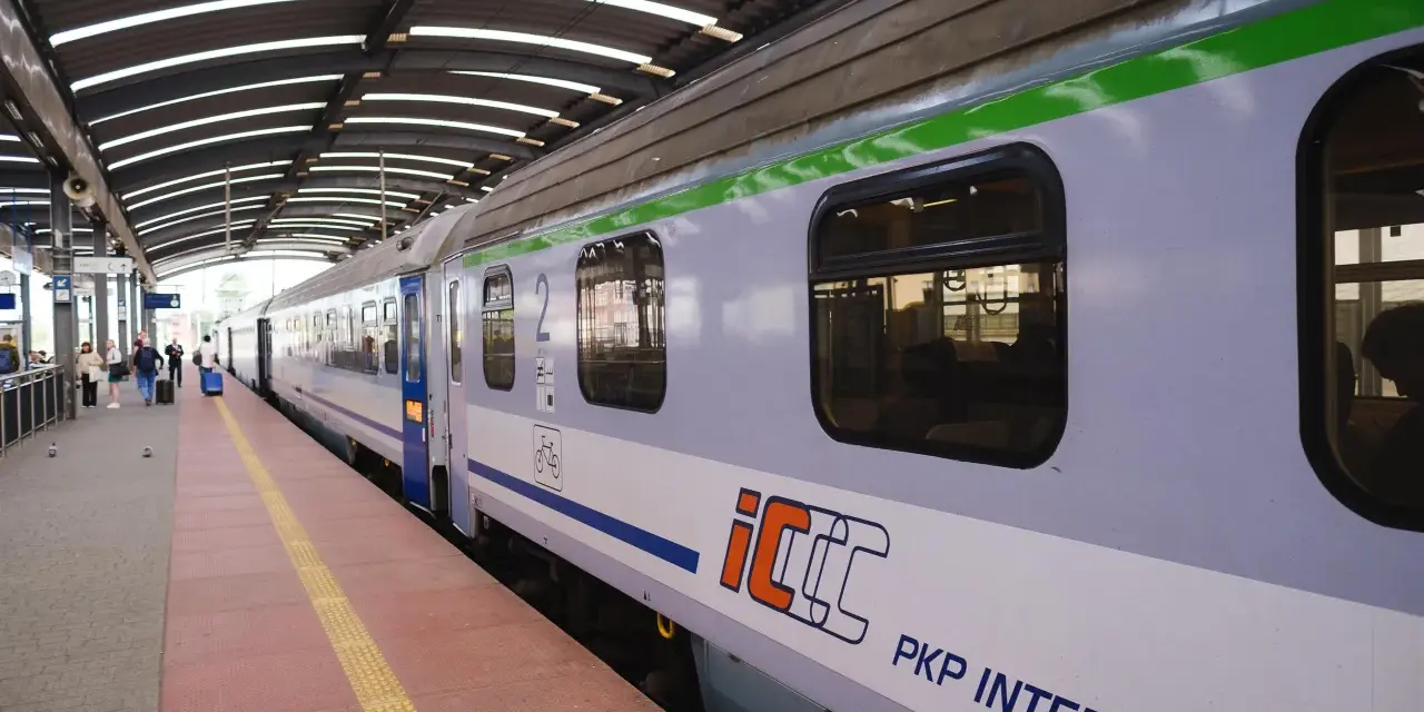 Pociąg PKP Intercity na peronie, z widocznymi oknami i logo.