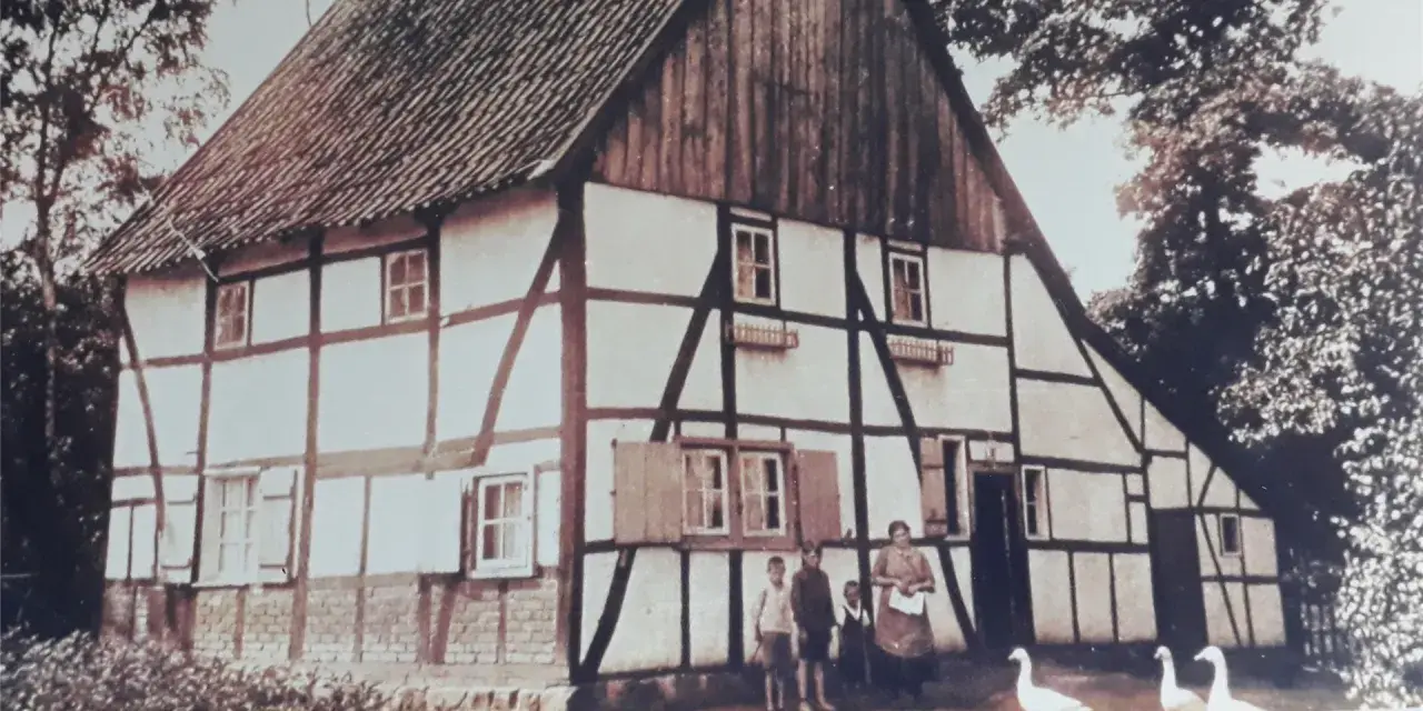 Fachwerkhaus in Lohburg, Waltrop, mit Familie und Gänsen vor dem Haus.