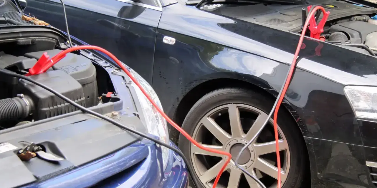 Zwei Autos werden mit Starthilfekabeln verbunden, um die Batterie zu starten.