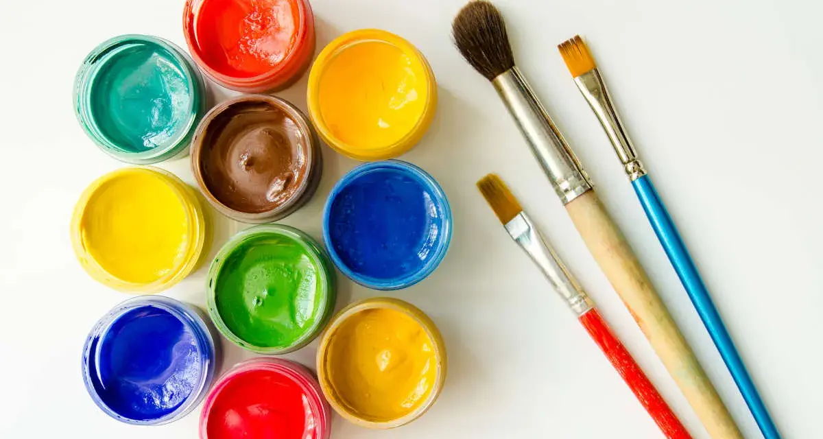 Tarros de temperas de colores vibrantes y pinceles listos para pintar.