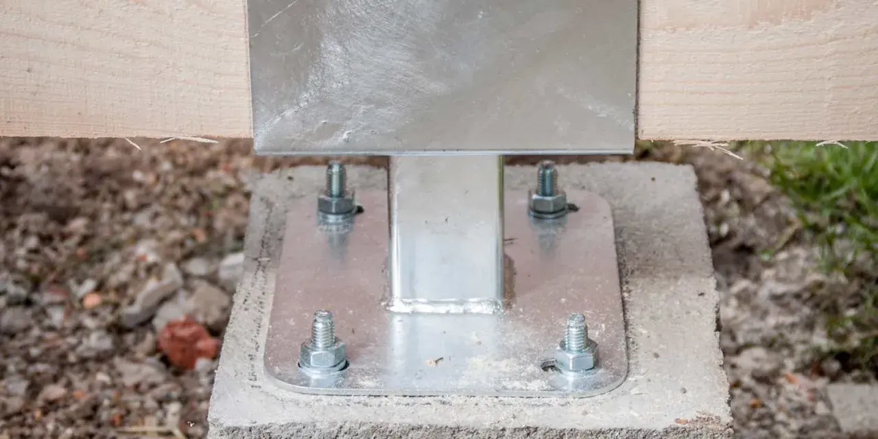 Pied de poteau métallique fixé sur un plot béton à enterrer, soutenant une poutre en bois.