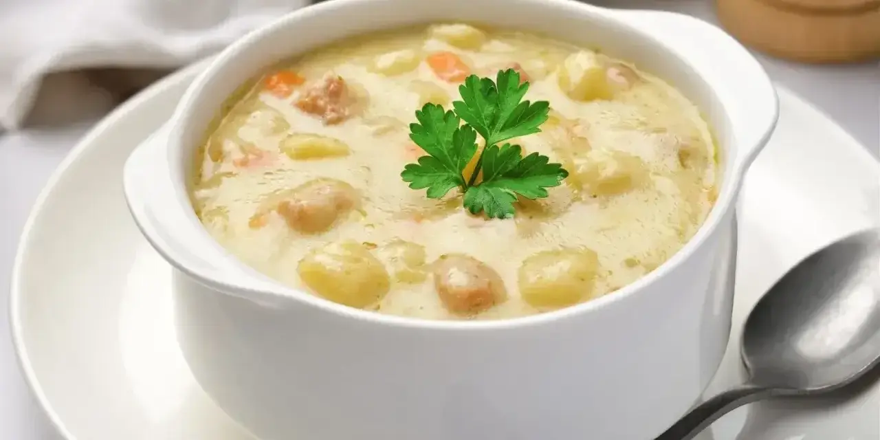 Babcina zalewajka przepis: kremowa zupa z ziemniakami, marchewką i kiełbasą, udekorowana natką pietruszki. Pyszne danie na chłodne dni.