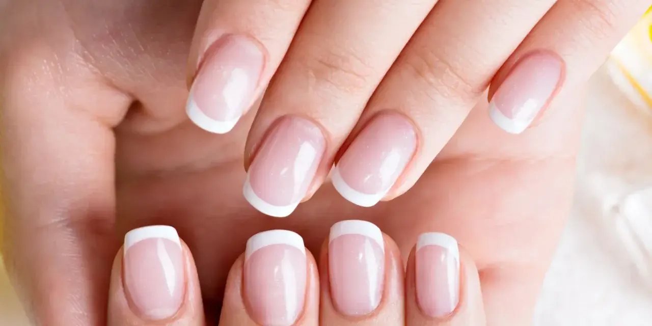 Dłonie z idealnym french manicure, gdzie białe końcówki paznokci lśnią jak tytanowe paznokcie.