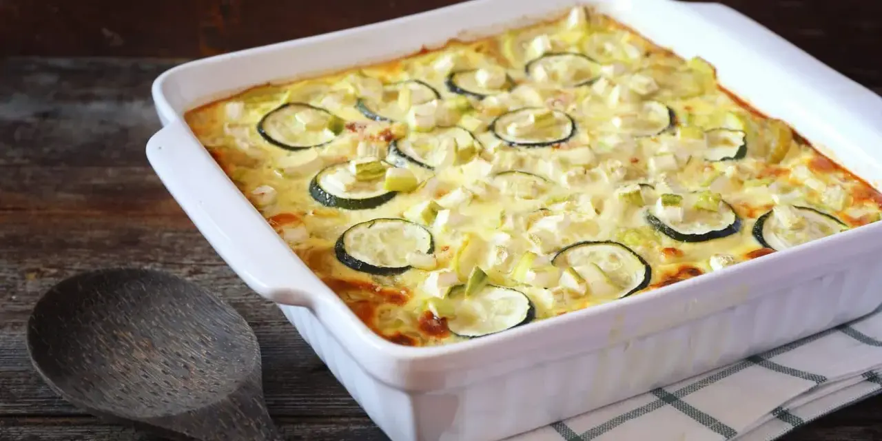 Un délicieux gratin de courgettes, prêt à être dégusté, avec des rondelles de courgettes et des morceaux de poireau dans une sauce crémeuse.