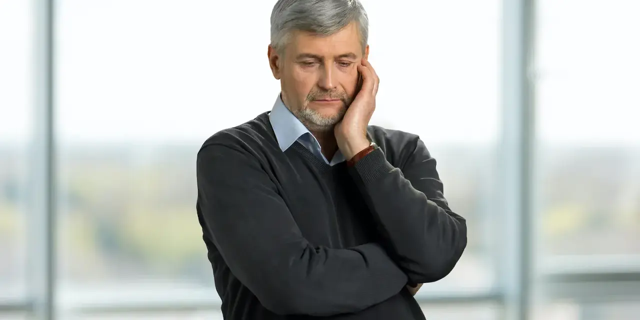 Pracujący rencista zamyślony, jakby rozważał zwolnienie lekarskie.