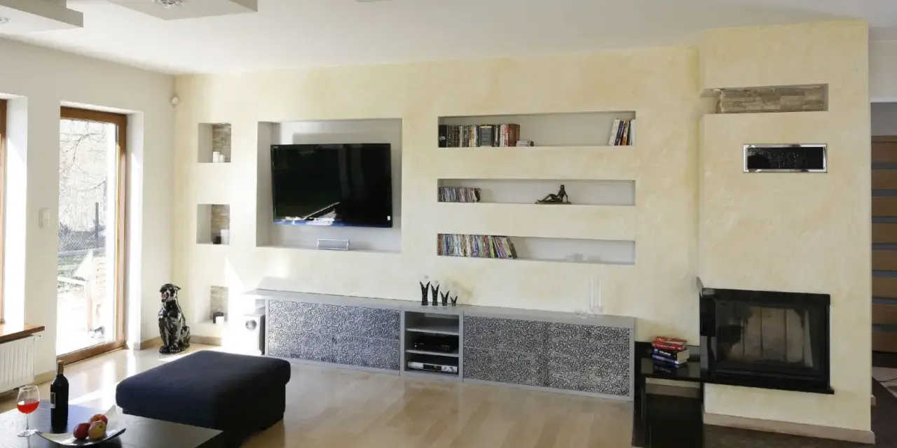 Nowoczesna zabudowa pod telewizor z karton gipsu, z wnękami na książki i dekoracje.