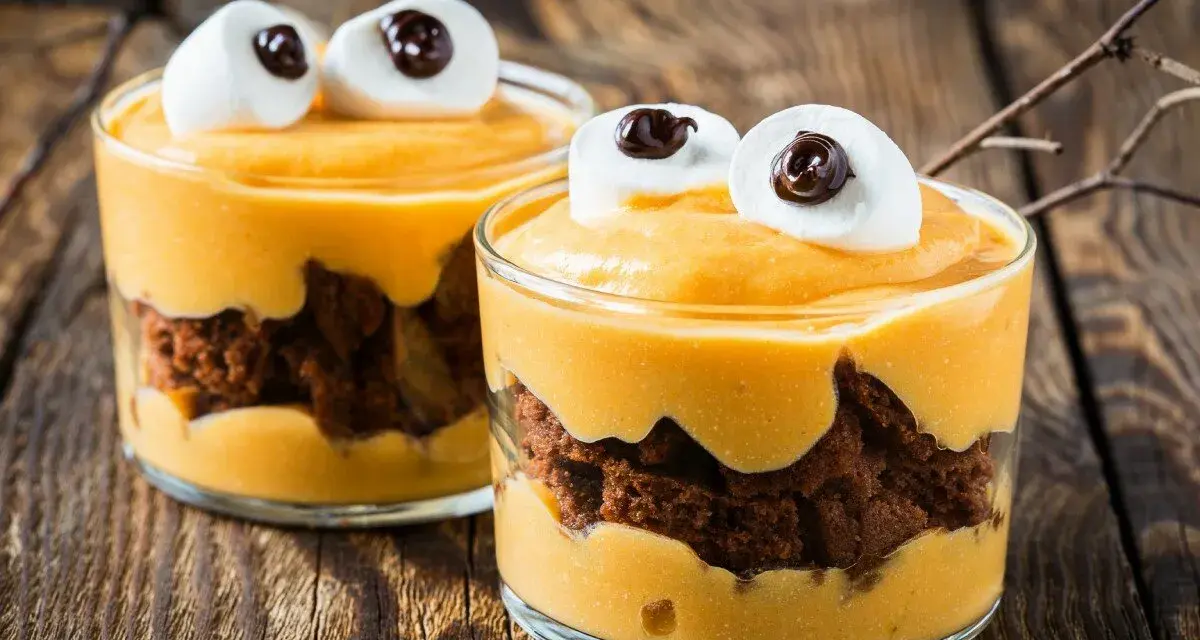 Przepis na Halloween: deser z mascarpone i ciastkiem czekoladowym, ozdobiony piankami jak oczy potwora.