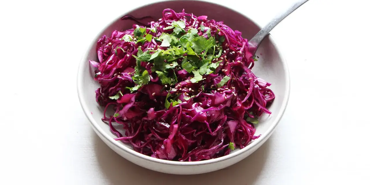 Salade colorée de chou rouge râpé, garnie de coriandre fraîche et de graines de sésame. Une idée simple pour une recette chou rouge savoureuse.