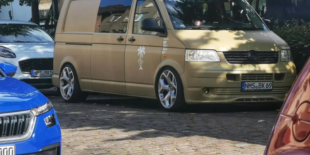 Złoty bus, przeróbka busa na kampera przepisy. Stylowe felgi, naklejki i palma na boku.
