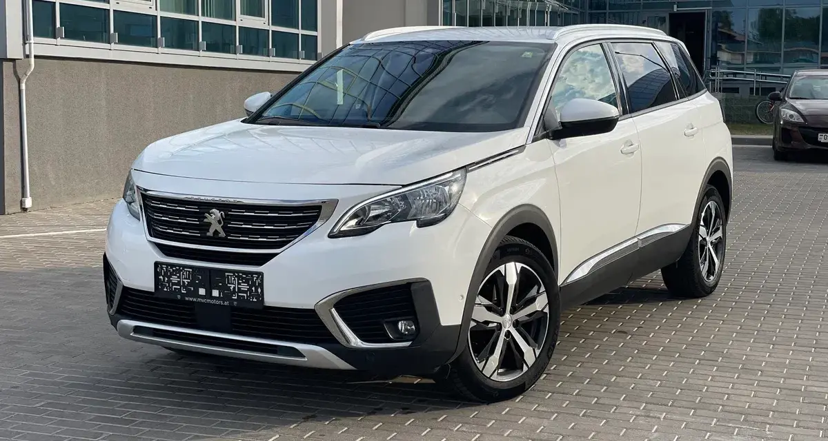 Biały Peugeot 5008 na parkingu. Wiele osób szuka peugeot 5008 opinie, ten SUV to świetny wybór.
