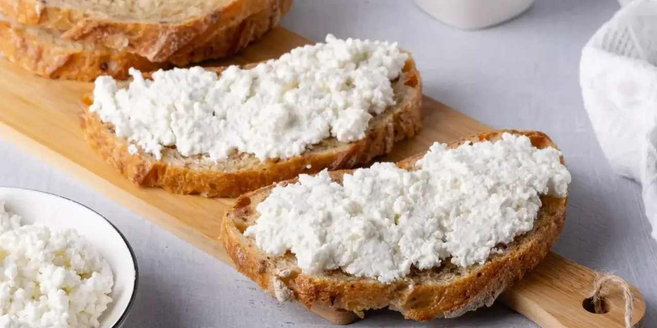 Fette di pane rustico con abbondante ricotta fresca, pronte per gustose ricette con ricotta.