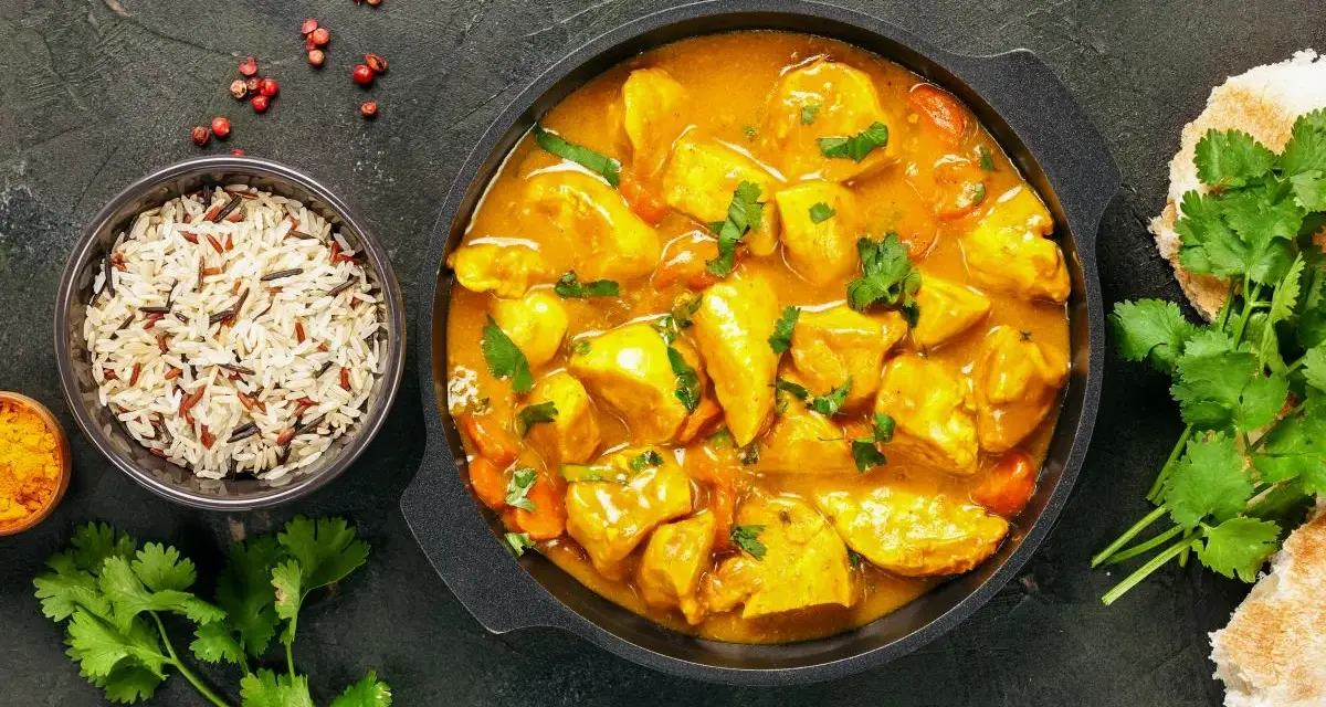 Kurczak w sosie curry z ryżem, kolendrą i pieczywem.