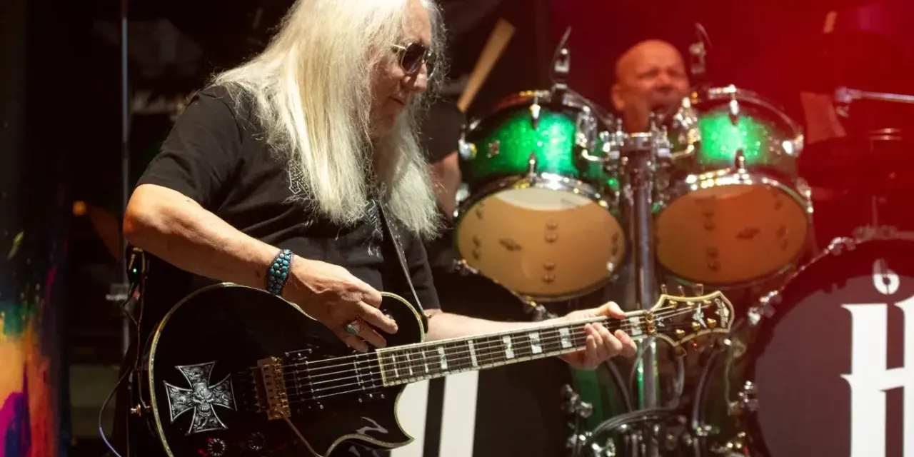 Uriah Heep członkowie na scenie. Mick Box gra na gitarze, a za nim perkusista.