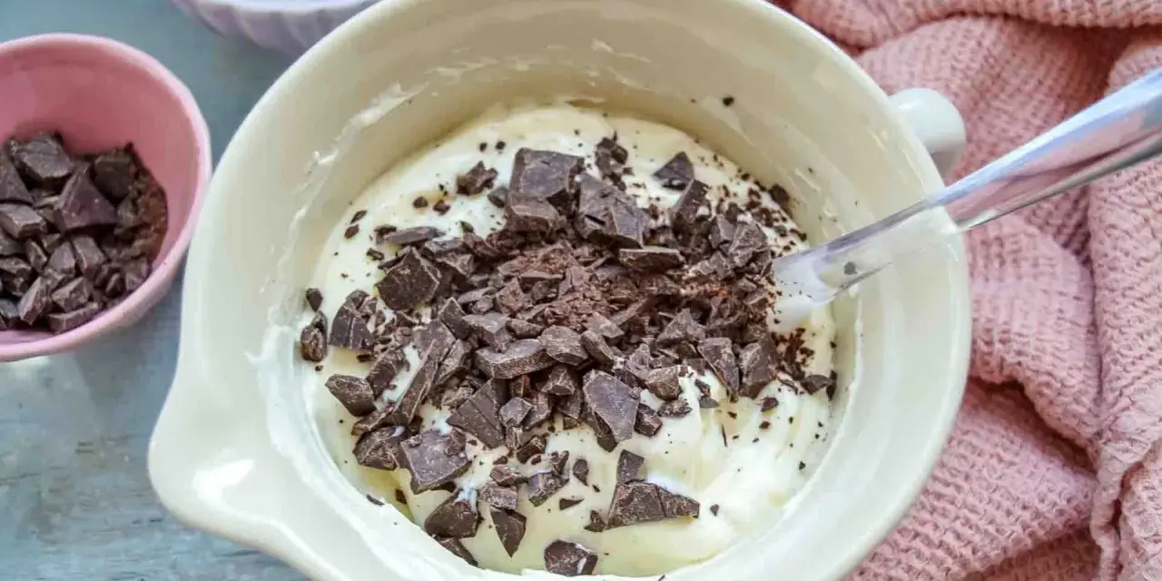 Cremige Masse mit Schokoladenstückchen, bereit für das Herrencreme Rezept. Kleine Schale mit gehackter Schokolade daneben.