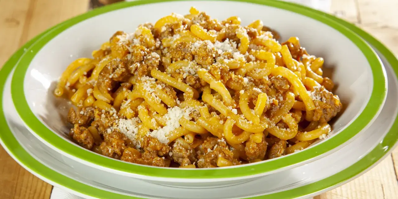 Piatto di gramigna alla salsiccia, condita con ragù saporito e una spolverata di parmigiano.