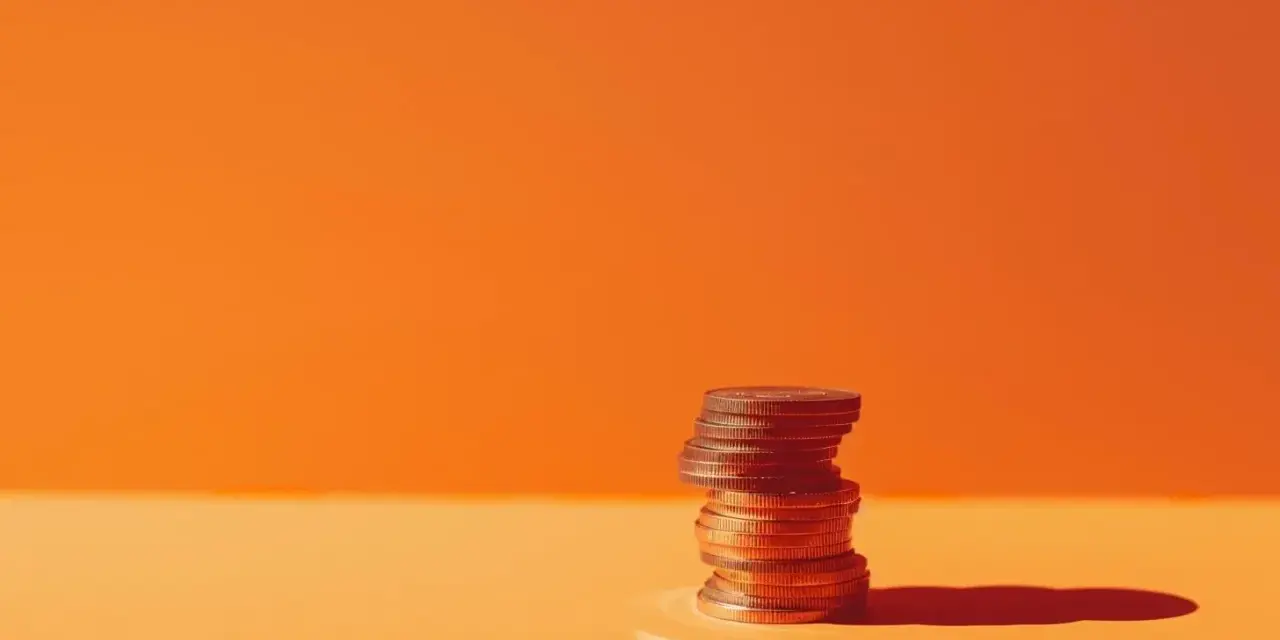 A stack of coins on an orange surface, symbolizing the business account requirements for financial growth.