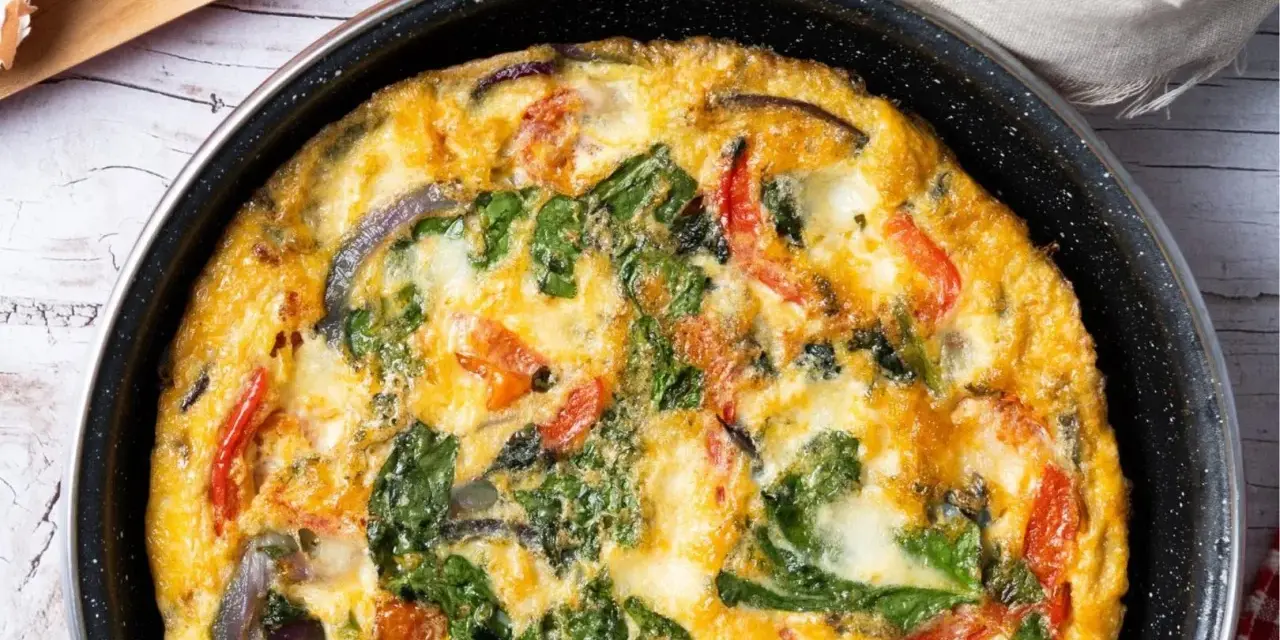 Pyszny omlet z cukinią, pomidorami i szpinakiem, zapieczony w patelni. Idealny na śniadanie lub lekki obiad.