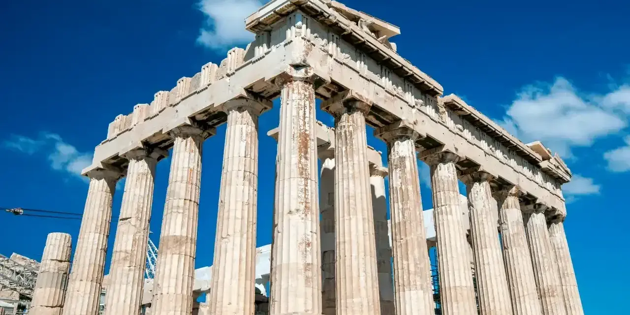 Le Parthénon, temple d'Athéna, se dresse majestueusement sous un ciel bleu éclatant, ses colonnes doriques témoignant de la grandeur de l'Acropole d'Athènes.
