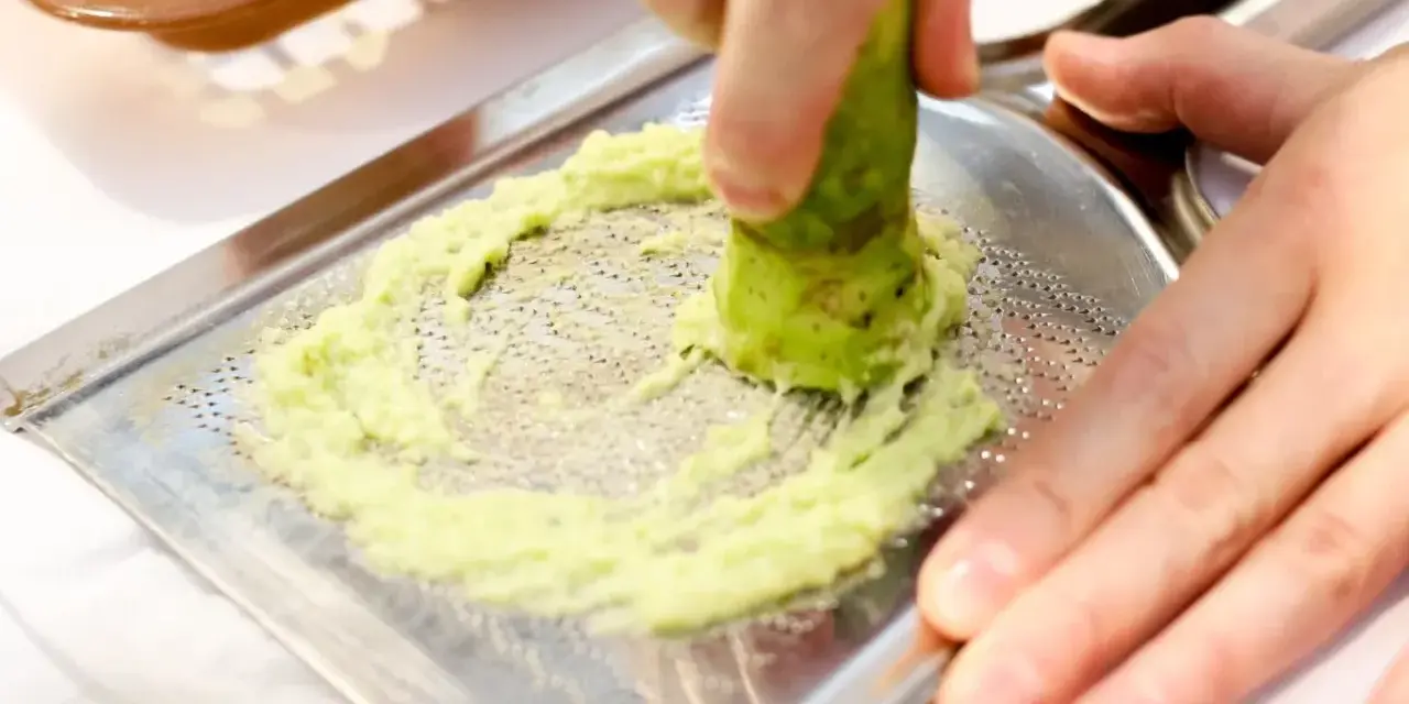Świeże wasabi jest tarte na metalowej tarce, tworząc zieloną pastę. To właśnie tak powstaje prawdziwe wasabi.