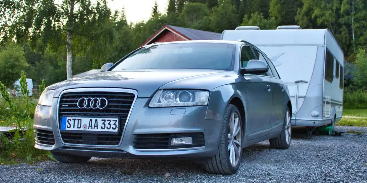 Grauer Audi A6 F4 Kombi mit Wohnwagen im Hintergrund, bereit für den Urlaub.