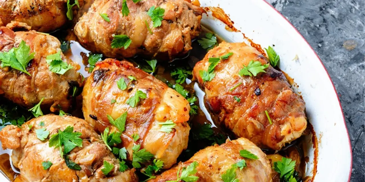 Involtini di carne dorati e succulenti, guarniti con prezzemolo fresco, cotti in una teglia bianca.