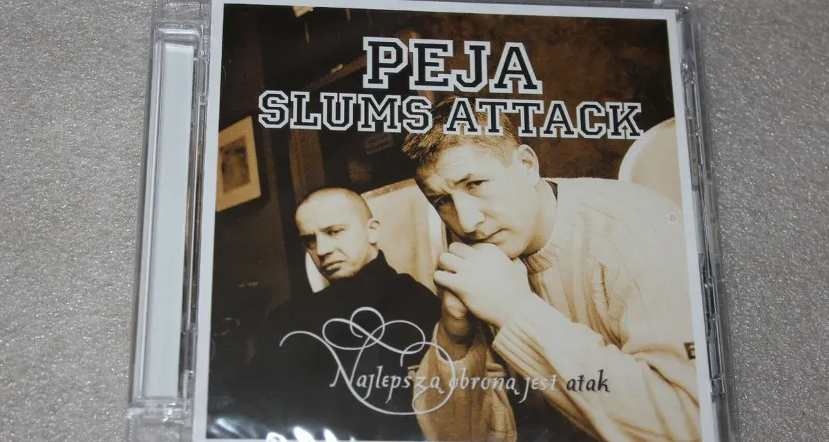 Okładka płyty "Peja Slums Attack - Najlepsza obrona jest atak". Dwóch mężczyzn, jeden w czarnym golfie, drugi w swetrze, spogląda wprost na widza.