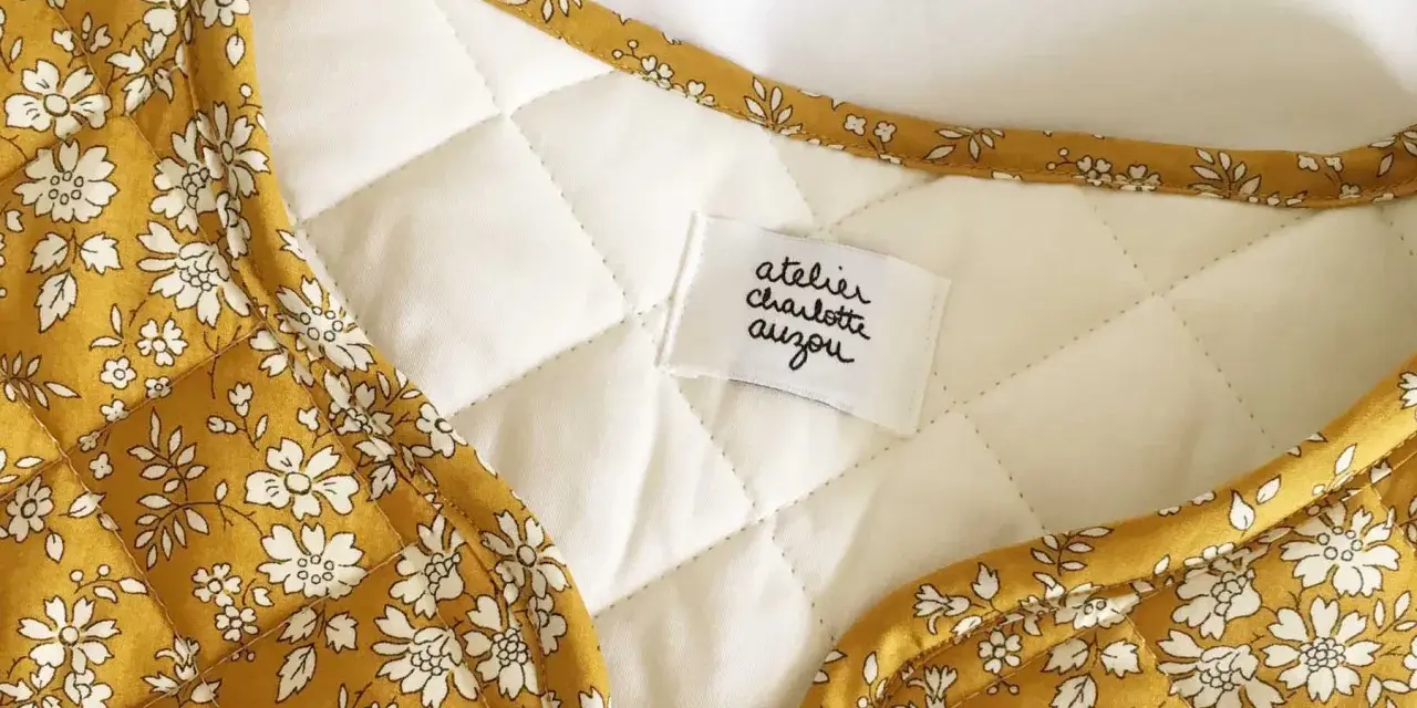 Détail d'une veste matelassée femme avec un tissu fleuri jaune moutarde. Un patron gratuit pour créer ce modèle est disponible.