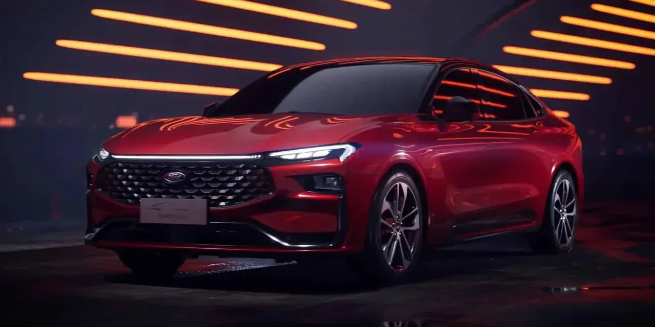 Czerwony Ford Mondeo MK6 z nowoczesnym designem, błyszczącym grillem i ostrymi światłami LED, prezentowany na tle pomarańczowych świateł.