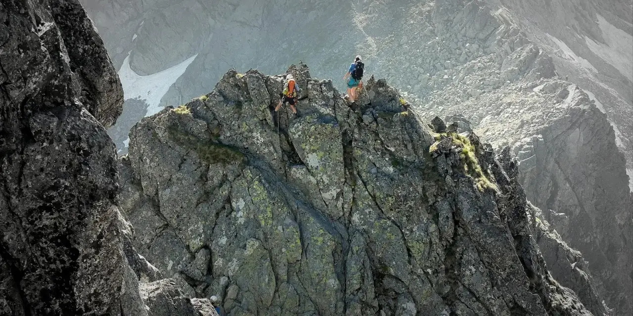 Dwóch alpinistów pokonuje skalisty grzbiet. Jeden z nich zjeżdża na linie, drugi czeka na szczycie. To trudna droga Martina na Gerlach.