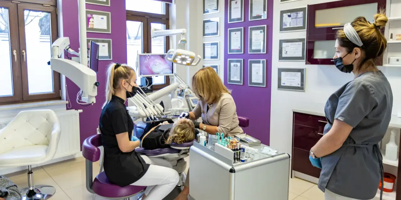 Gabinet stomatologiczny z trzema osobami, w tym dentystką przy pacjencie.