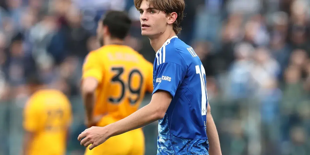 Joven futbolista Nico Paz, con el dorsal 10 en su camiseta azul, mira atentamente el partido.