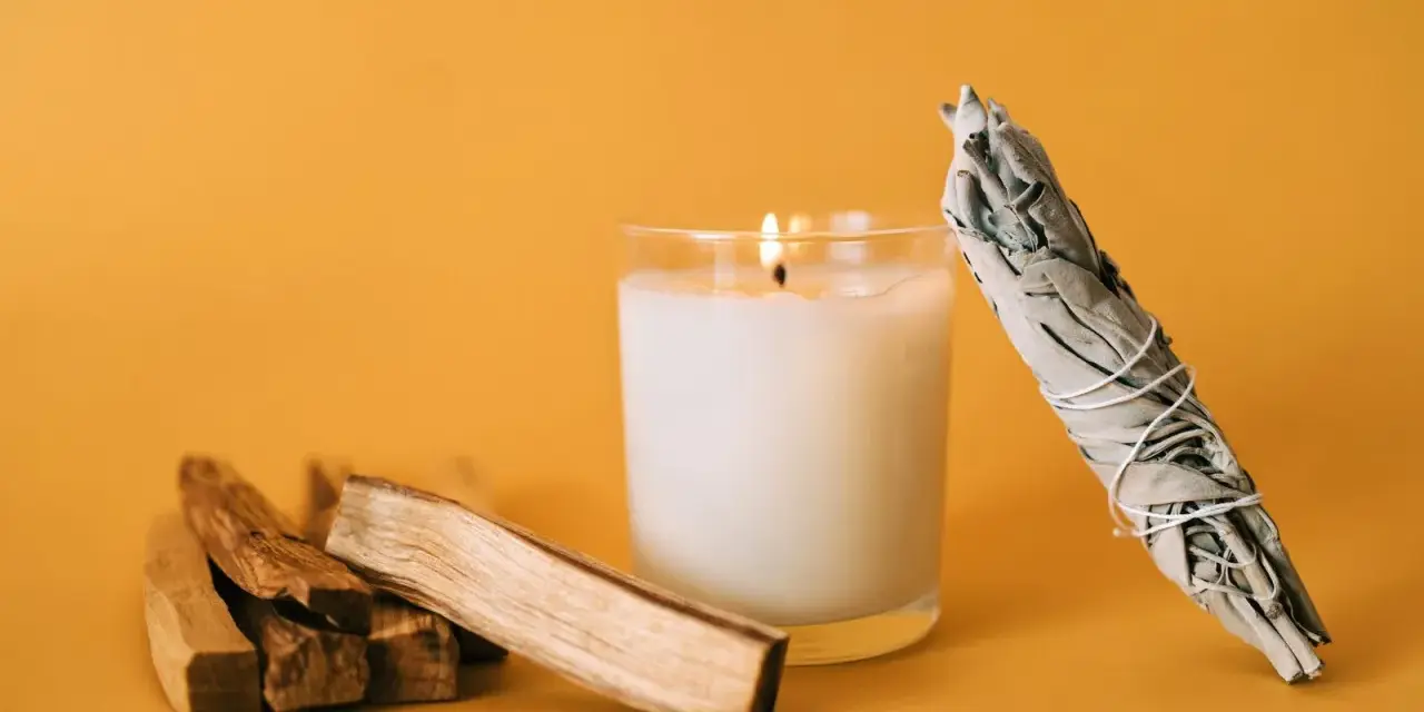 Palosanto, vela encendida y manojo de salvia. Prepara tu espacio para como quemar palo santo y purificar el ambiente.