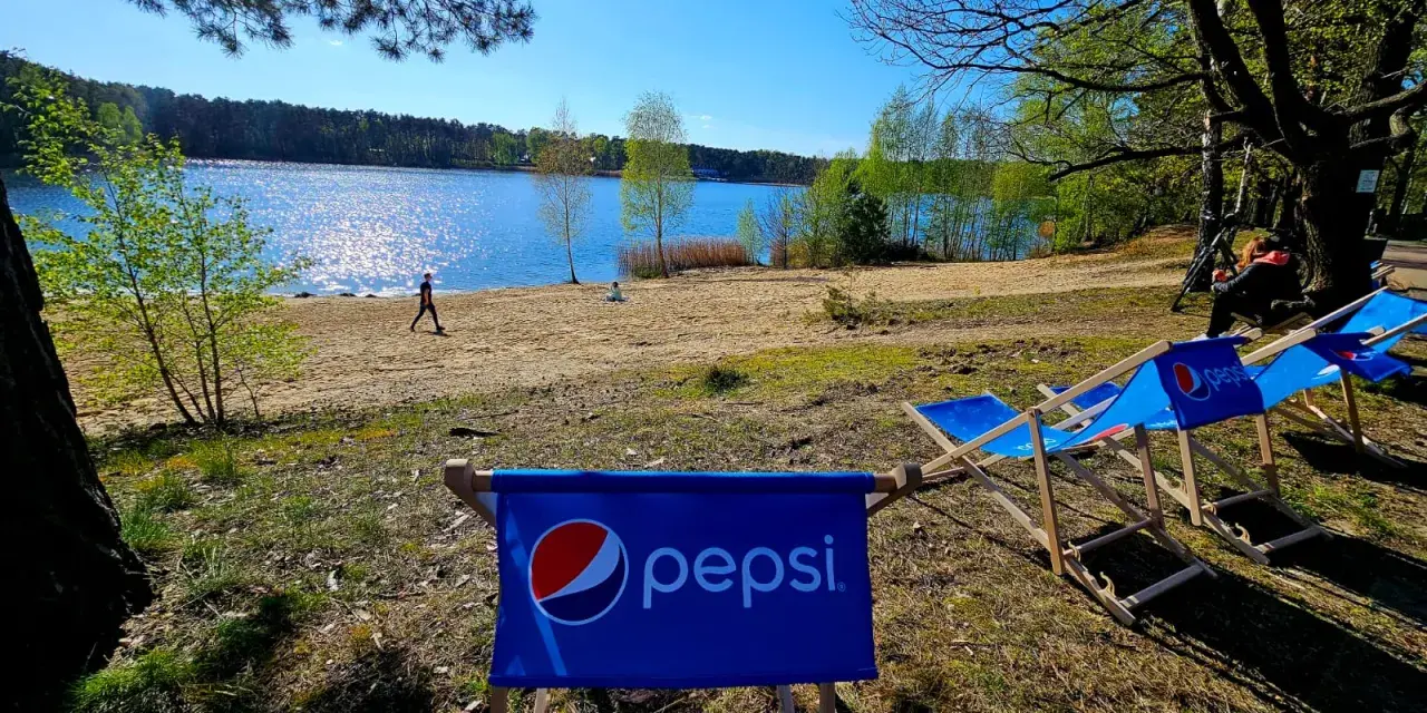 Słoneczny dzień nad jeziorem, leżaki z logo Pepsi czekają na gości turawa camp.