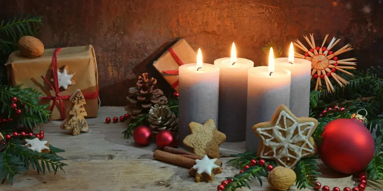 Vier brennende Kerzen im **Hintergrund Adventszeit**, umgeben von Tannenzweigen, Geschenken, Nüssen und Weihnachtsplätzchen.