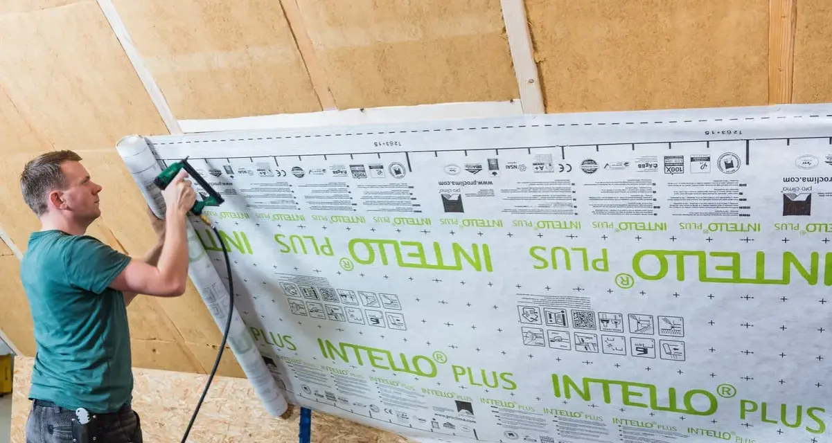 Mann bringt mit einem Tacker eine Dampfbremse an. Die Folie ist mit "INTELLO PLUS" bedruckt.
