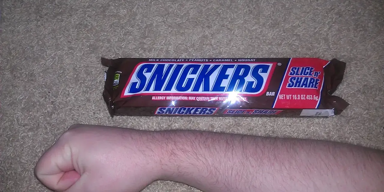 Ręka obok opakowania Snickersów. Zastanawiasz się nad snickers kcal?