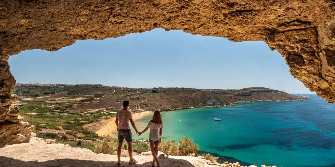 Para zakochanych podziwia widok na turkusowe morze i plażę z jaskini. Malta w styczniu pogoda idealna na spacer.