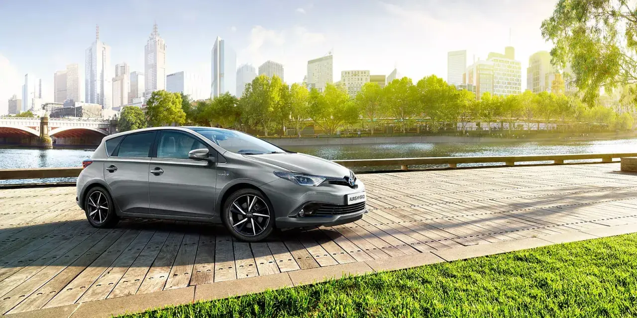 Szary Toyota Auris Hybrid na drewnianym pomoście, z miastem w tle. Jaki olej do tego modelu?